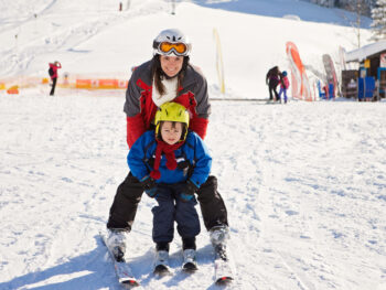 young woman and her kid enjoying on skis