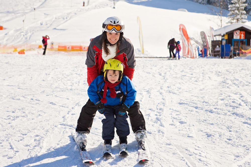 young woman and her kid enjoying on skis