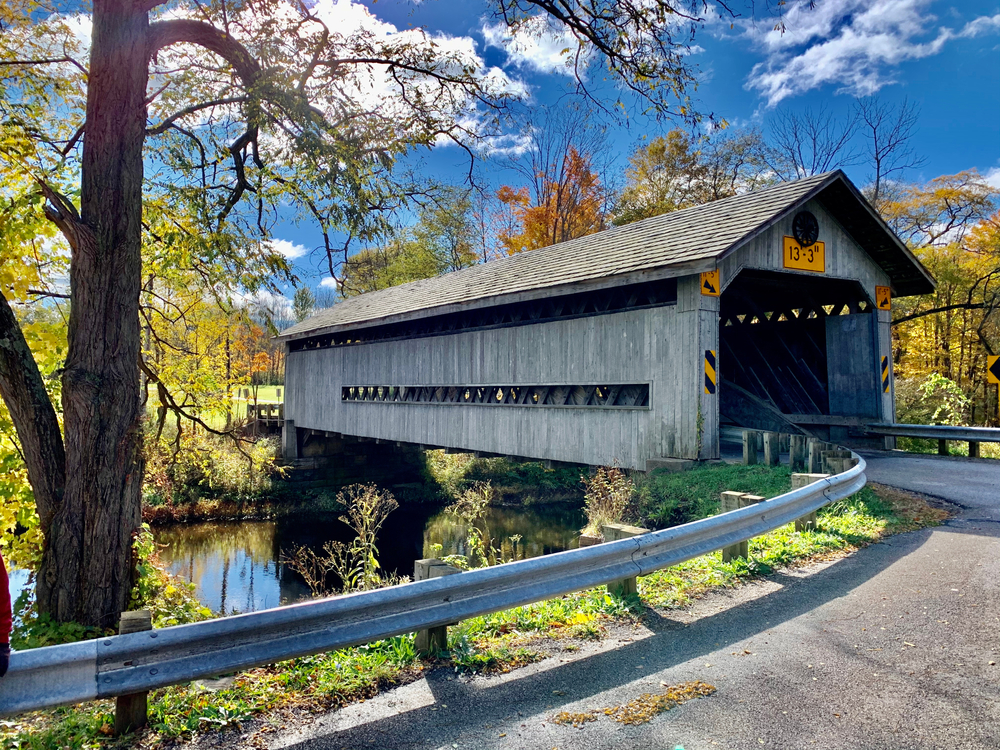 Gray colored scenic covered bridge in Ashtabula County, Ohio with a bright blue sky
