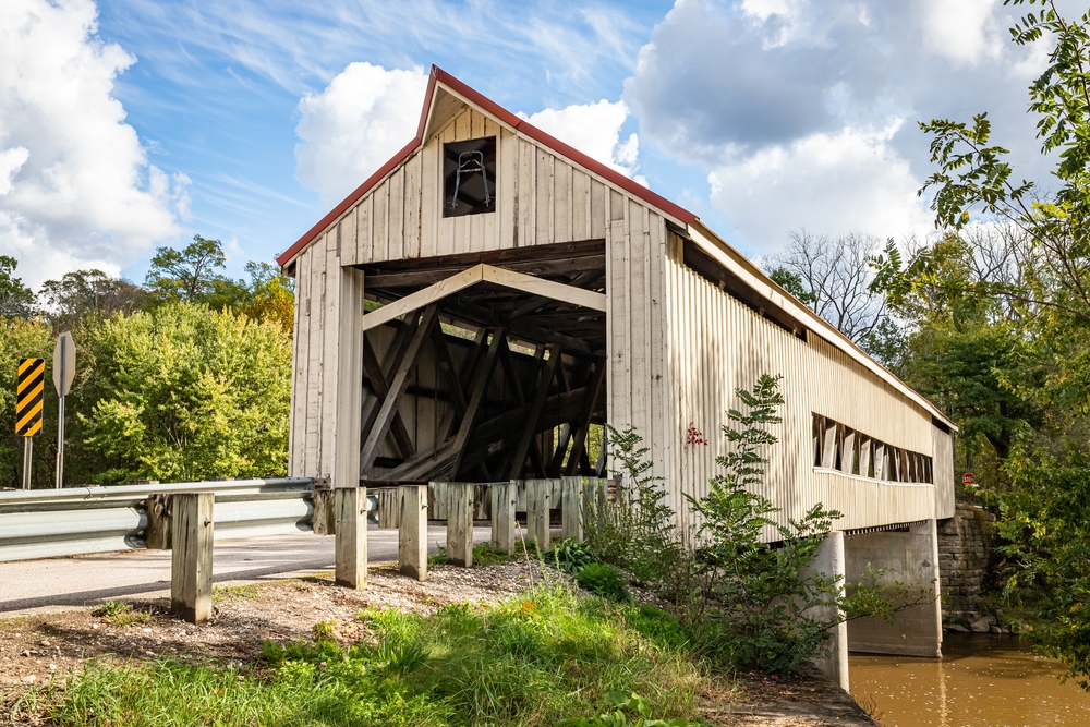 light-colored wooden bridge spanning river surrounded by greenery