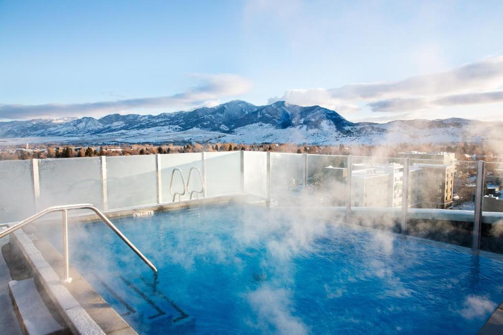 Hotel pool on the rooftop with steam coming off looking out over the mountains.