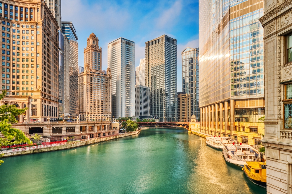 Chicago Downtown Cityscape with Chicago River at Sunrise, and boats by the buildings. 