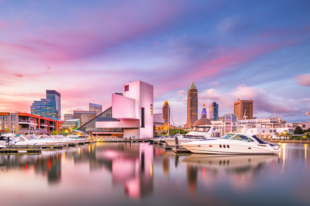 Cleveland, Ohio, USA downtown city skyline and harbor at twilight. There is a boat and the buildings appear pink. 