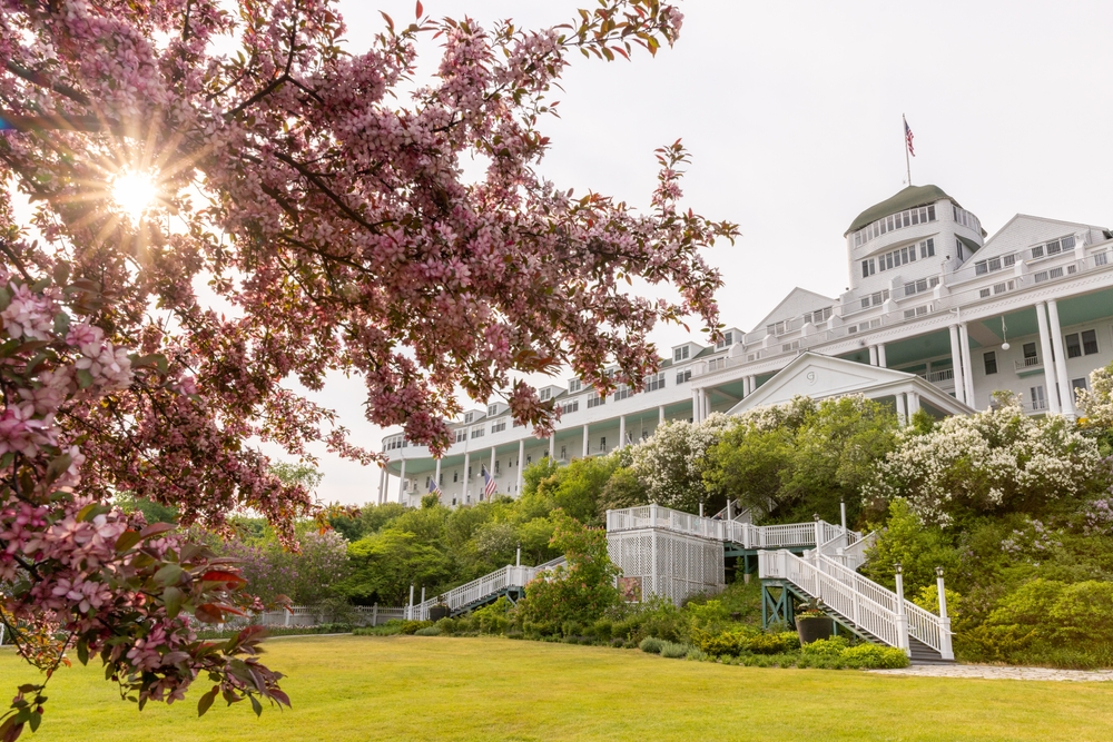Sunflare through a pink blooming crabapple tree in front of the Grand Hotel on Mackinac Island, Michigan. The article is about spring break in the Midwest.