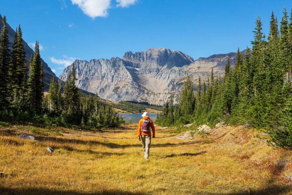 Hiker  walking towards a lake and mountains.  