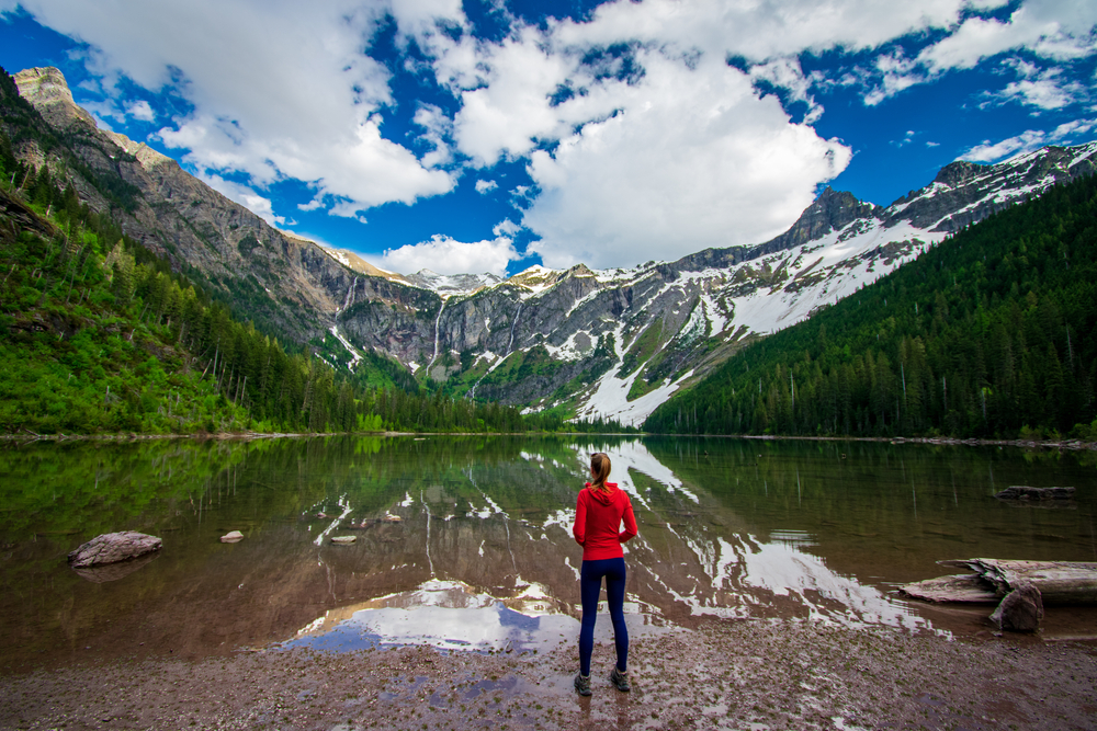 Woman admiring the beauty of nature. She is stood in front of a lake with mountains, 