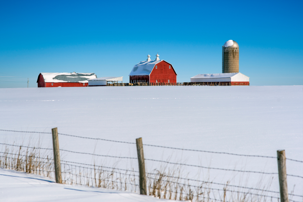 Iowa farmland in winter time showing red barn. The article is about Midwest Winter Road Trips.