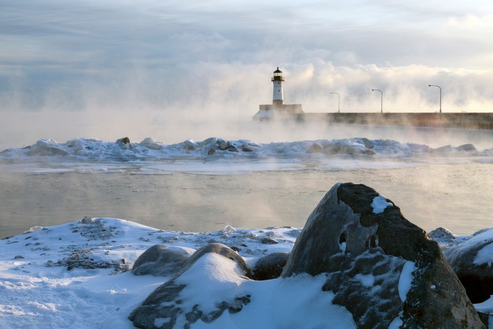 Steam rising on the shore of Lake Superior with Duluth North Pier Lighthouse in the fog on a subzero morning. 