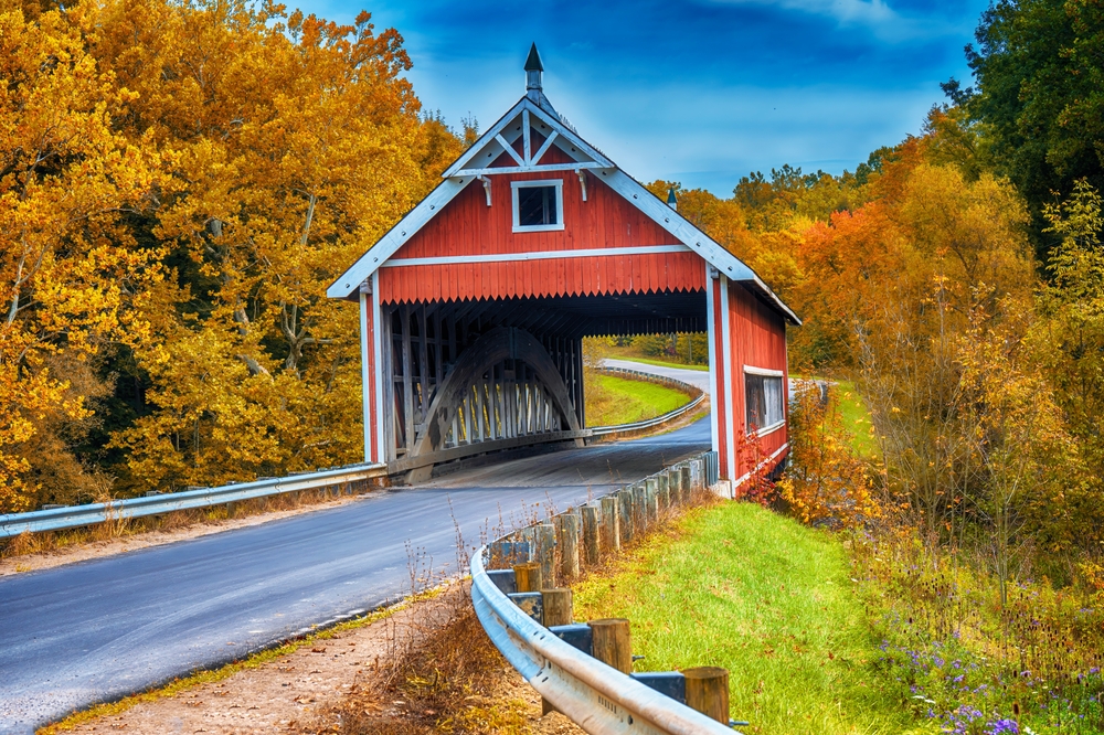 red covered bridge surrounded by fall foliage midwest fall scenic drives