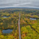 road passing through a forest with lakes during fall season midwest fall scenic drives