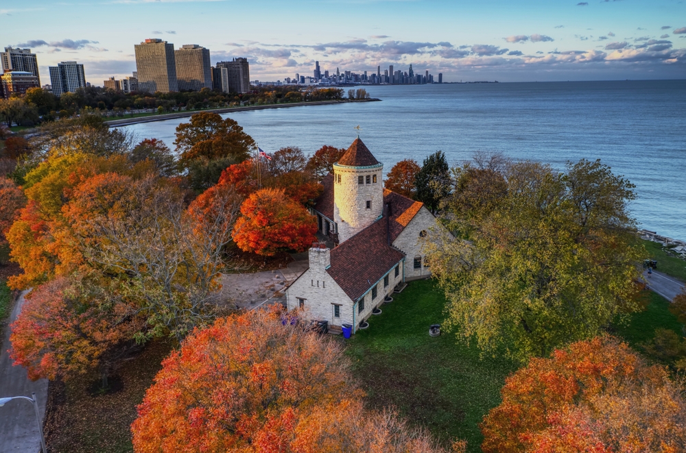 view of an old church in a park with ocean and buildings behind it