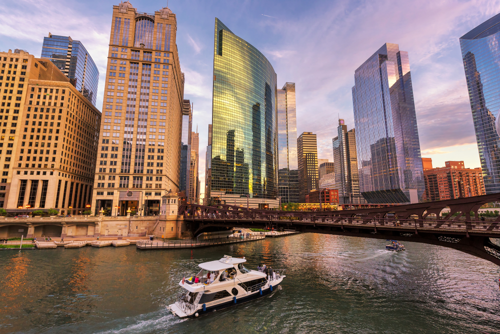 ship passing under a bridge with skyscrapers around it