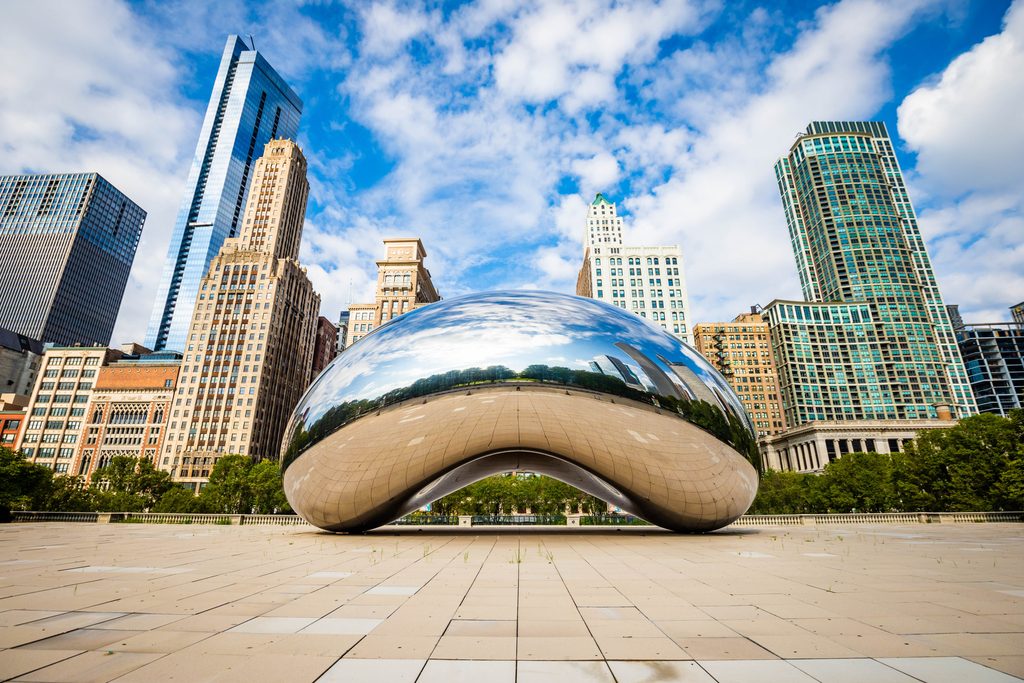 Famous Cloud Gate Chicago bean landmark at day nobody around in summer. there are tall buildings in the background. 