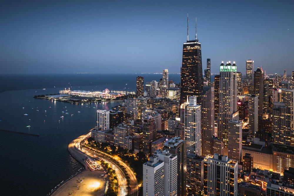 Aerial view of city skyline at night. Showing the buildings and a lake all with lights on. 